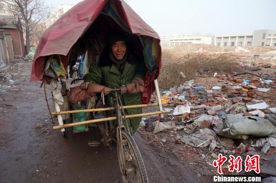 圖為老人走出窩棚，推著三輪車準(zhǔn)備出去撿拾廢品。周小云 攝