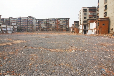 為降塵，旮旯王村拆遷后裸露的地面上鋪了一層石子。